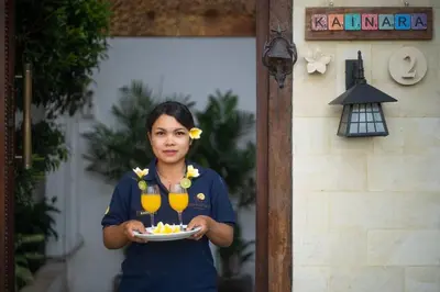 a woman holding a plate with two glasses of wine at Villa Kainara 2 - Cozy villa in center of Seminyak in Seminyak