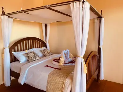 a bedroom with a white bed with a canopy at Giri's Villa Jimbaran in Jimbaran