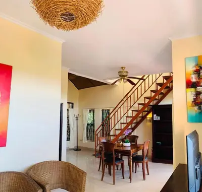 a dining room with a table and a staircase at Giri's Villa Jimbaran in Jimbaran
