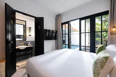 a bedroom with a large white bed and a bathroom at Martini Beachside Villa 3 in Canggu