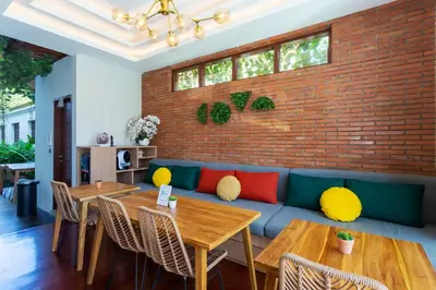 a restaurant with tables and a couch and a brick wall at Cove Ransha Stay in Sanur