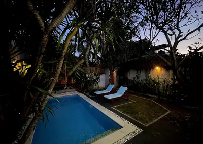 a swimming pool with a chair next to a house at Villa Majegau 2 Seminyak in Seminyak