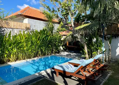 a pool with two lounge chairs next to a house at Villa Majegau 2 Seminyak in Seminyak