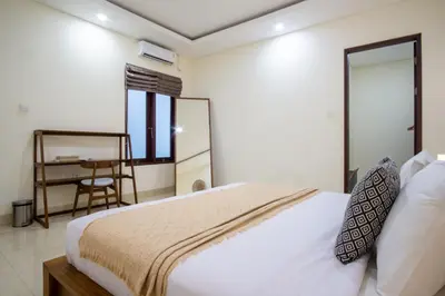 a bedroom with a bed and a desk and a chair at Villa Maxima by Maheswara in Canggu