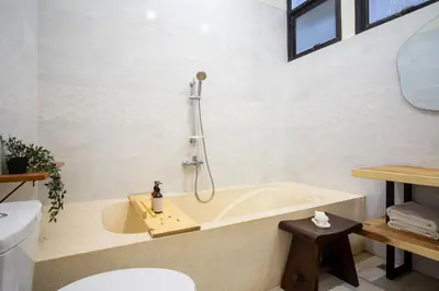 a bathroom with a tub and a toilet at Villa Maxima by Maheswara in Canggu