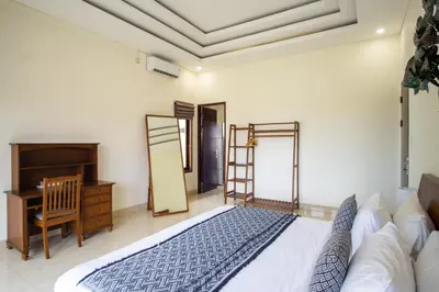 a bedroom with a bed and a desk and a mirror at Villa Maxima by Maheswara in Canggu