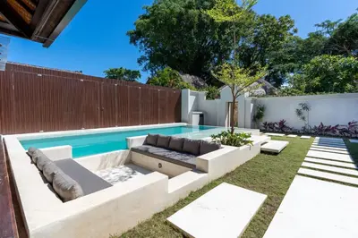 a backyard with a pool with a couch and aitating at Green Jimbaran Bay Villa in Jimbaran