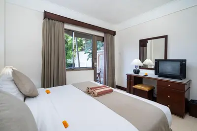 a bedroom with a white bed and a television at Beach Apartment inside Resort Walking Distance to the beach in Seminyak