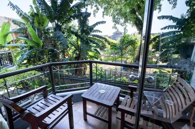two chairs and a table on a balcony with palm trees at Beach Apartment inside Resort Walking Distance to the beach in Seminyak