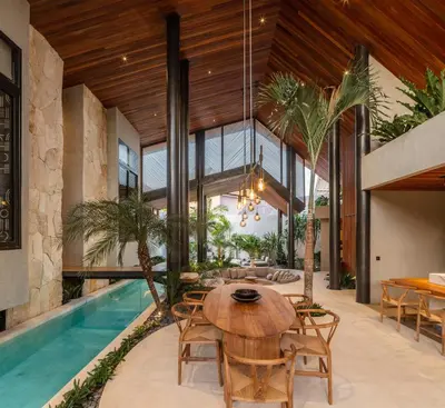 an indoor dining area with a table and chairs and a pool at Can Maestro Bali by House of Winds - Lush Sanctuary near Canggu in Kerobokan