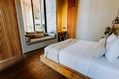 a bedroom with a white bed and a couch at Villa FEH Bali by House of Winds - Neo Tropical Eden near Canggu in Kerobokan