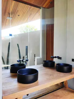 three black sinks on a wooden counter in a bathroom at Villa FEH Bali by House of Winds - Neo Tropical Eden near Canggu in Kerobokan