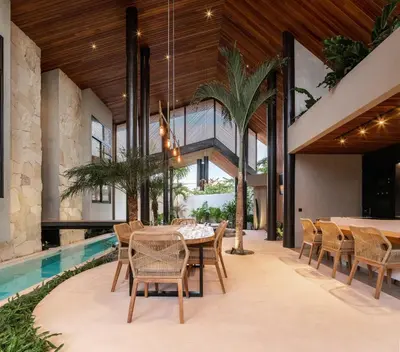 an open dining room with a table and chairs and a pool at Villa FEH Bali by House of Winds - Neo Tropical Eden near Canggu in Kerobokan