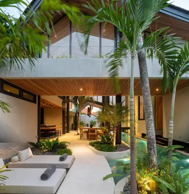 an external view of a villa with a swimming pool and palm trees at Villa Levante Bali by House of Winds - Tropical Oasis near Canggu in Kerobokan