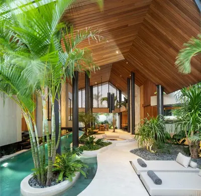 an indoor pool with palm trees and a wooden ceiling at Villa Levante Bali by House of Winds - Tropical Oasis near Canggu in Kerobokan