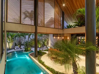 an indoor courtyard with a swimming pool and palm trees at Villa Levante Bali by House of Winds - Tropical Oasis near Canggu in Kerobokan