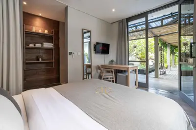 a bedroom with a large white bed and a table at Sin Nombre Bali - Sauna, Ice Bath & Roof Terrace in Canggu