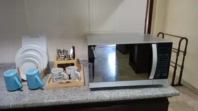 a microwave on top of a counter with mugs at Kun's Stay Private Apartments in Seminyak