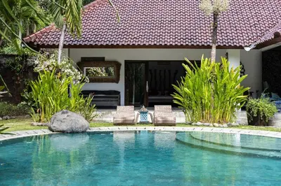 a swimming pool with two chairs and a house at Villa Permata Umalas - Relaxing Tropical Oasis in Seminyak