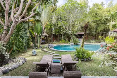 a backyard with a pool with picnic tables and chairs at Villa Permata Umalas - Relaxing Tropical Oasis in Seminyak