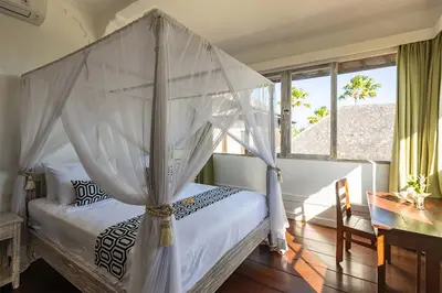 a bedroom with a canopy bed and a desk at Villa Nyama by Optimum Bali Villas in Seminyak