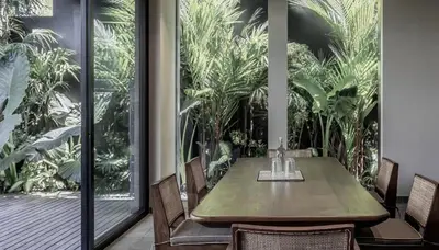 a table and chairs on a patio with plants at Black Villas Canggu Beach by OXO in Canggu