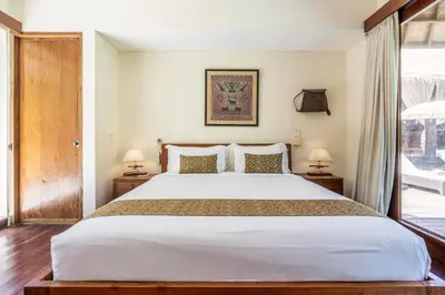 a bedroom with a large white bed and a window at Villa Ku Besar by Villa Finder in Dalung