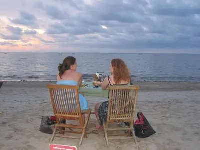 two women sitting at a table on the beach at The Open House Jimbaran Bali in Jimbaran