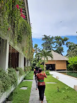 a group of people walking down a sidewalk next to a building at The Open House Jimbaran Bali in Jimbaran
