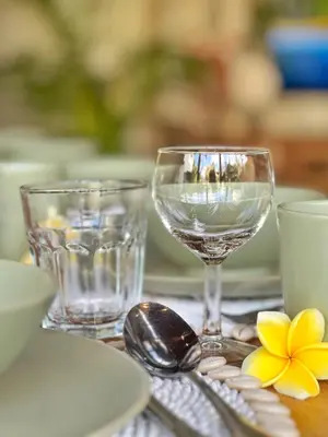 a table with two wine glasses and a plate and spoon at Villa Nicole 5BR Paradise, quiet area in Central Oberoi Seminyak in Seminyak