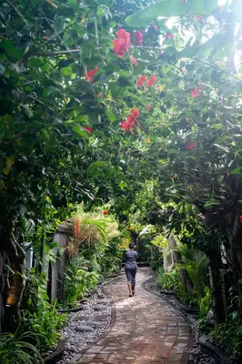 a woman walking down a brick path in a garden at The Bali Dream Suite Villa Seminyak in Seminyak