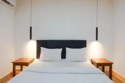 a bedroom with a large white bed with two tables at Kos 168 Jimbaran in Jimbaran