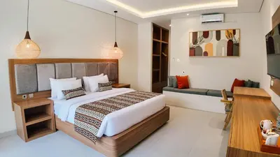 a bedroom with a bed and a desk and a couch at Casa Wina Kuta by The Wina Resorts in Kuta