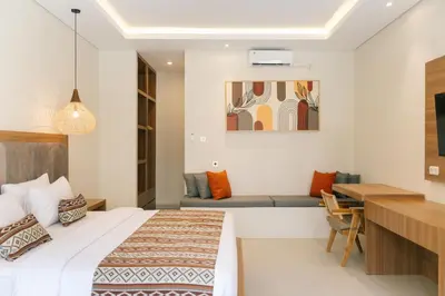 a bedroom with a bed and a desk and a table at Casa Wina Kuta by The Wina Resorts in Kuta