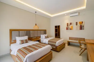 a hotel room with two beds and a desk at Casa Wina Kuta by The Wina Resorts in Kuta
