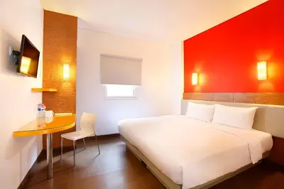 a bedroom with a white bed and a red wall at Amaris Hotel Dewi Sri - Bali in Legian