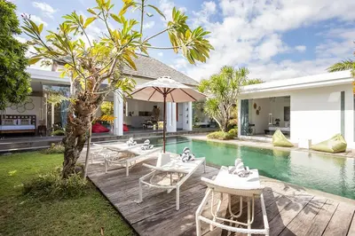 a pool with tables and chairs next to a house at Villa Bahia by Optimum Bali Villas in Seminyak