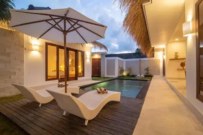 a patio with an umbrella and chairs and a pool at Simple & Magical Villas. Villa Sambali llI in Seminyak