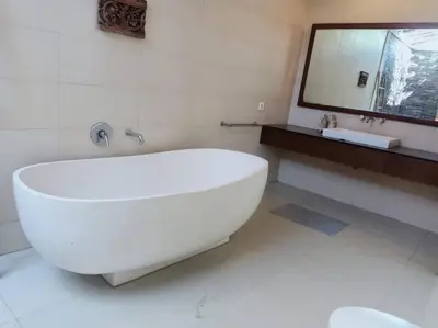 a white bathroom with a large tub and a mirror at Villa alula in Seminyak