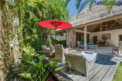 a patio with a red umbrella and chairs at The Tirta Naga Villas in Seminyak