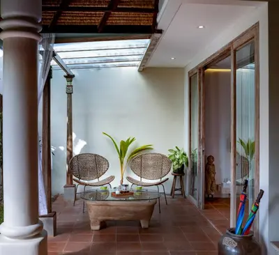 a patio with wicker chairs and a glass table at The Tirta Naga Villas in Seminyak