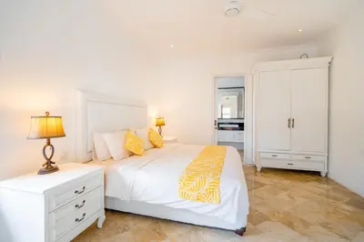 a bedroom with a white bed and a white cabinet at Kencana Villa Seminyak in Seminyak
