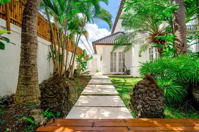 a walkway in front of a house with palm trees at Kencana Villa Seminyak in Seminyak