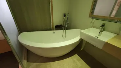 a bathroom with a white tub and a sink at Kimono Spa Hotel in Kuta