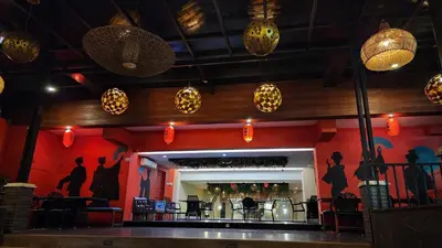 a restaurant with a red wall with people silhouettes at Kimono Spa Hotel in Kuta