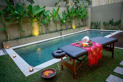 a table and chairs next to a swimming pool at The Kumpi Villas in Seminyak