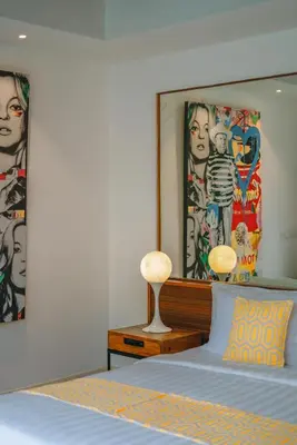 a bedroom with a bed and paintings on the wall at Villa Yasmee : Cozy and Modern 2 BR w/ Pool in Seminyak ! in Seminyak