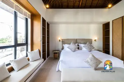 a bedroom with two white beds and a large window at Javine Villa - by Unicorn Villas Bali in Canggu