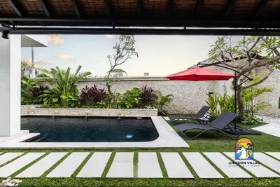 a swimming pool with a red umbrella and a chair at Javine Villa - by Unicorn Villas Bali in Canggu