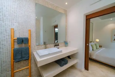 a bathroom with a sink and a bed and a mirror at Villa Anahata: Modern 2BR Villa w/ Pool in Seminyak ! in Seminyak